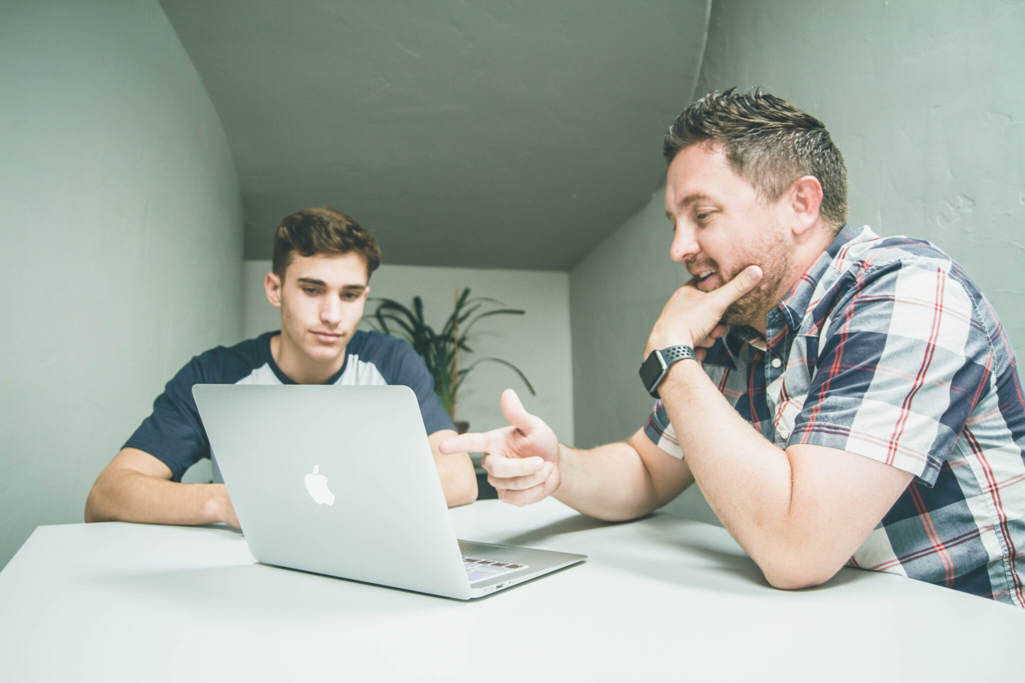 Twee medewerkers in overleg met elkaar met in het midden een laptop.