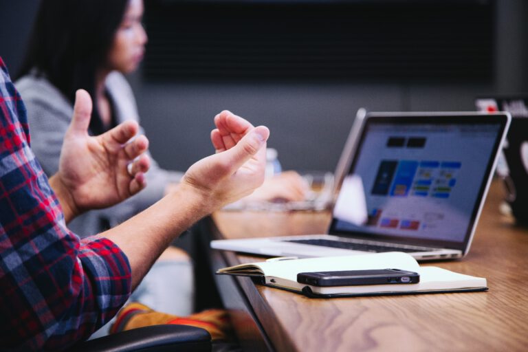 Medewerkers in vergadering met in het zicht een laptop, notitieblok en telefoon