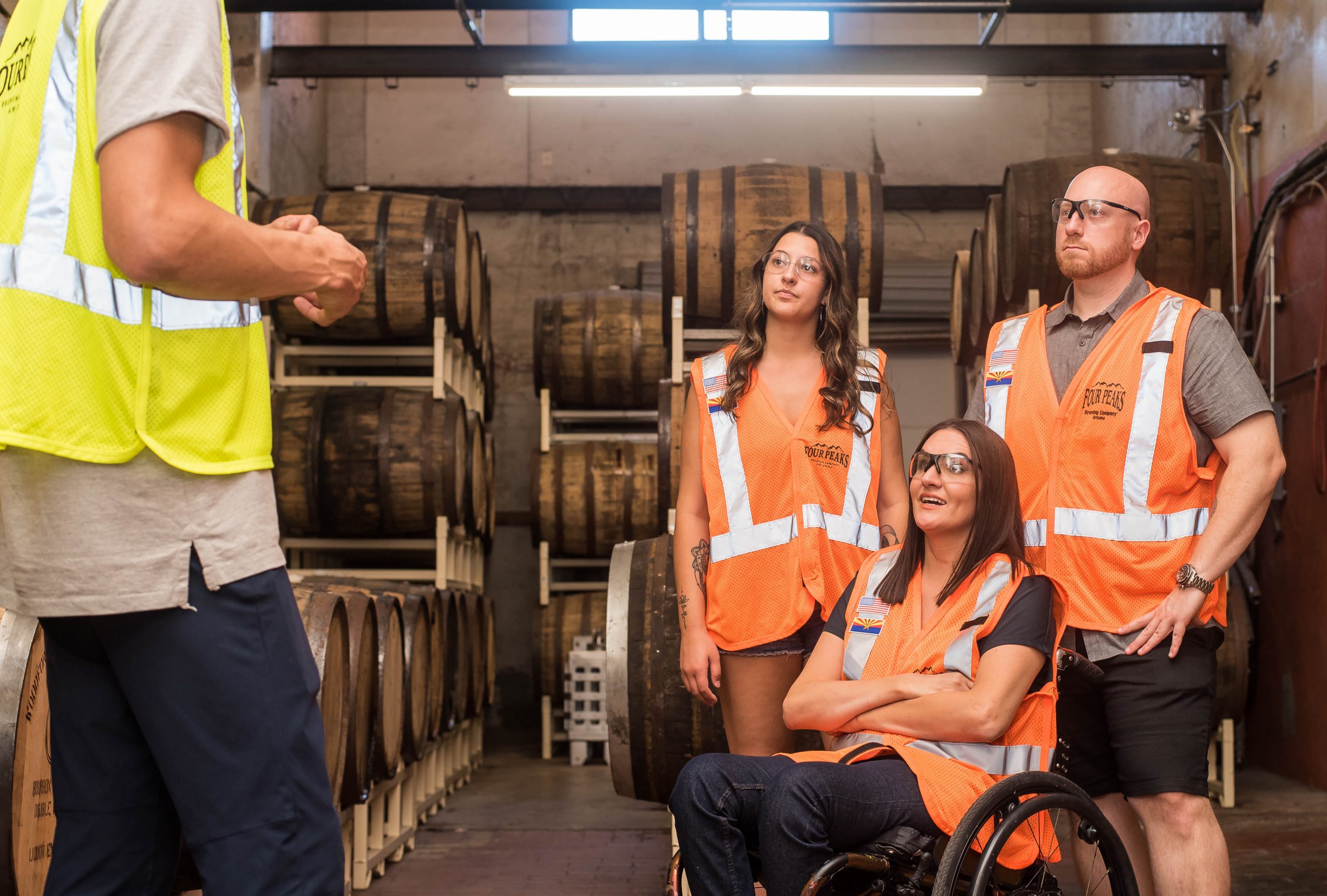Vier medewerkers met oranje hesjes aan, waarbij de ene medewerker de andere drie medewerker iets verteld.